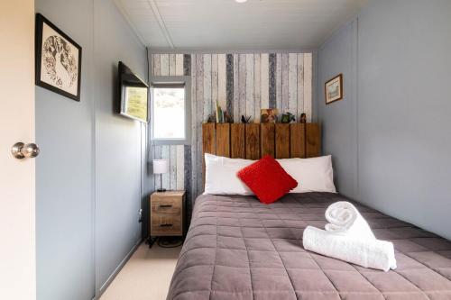 a bedroom with a large bed with red pillows at The Woolshed in Lake Tarawera