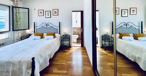 ein Schlafzimmer mit zwei Betten und einem Spiegel in der Unterkunft Holibai, Vila Natercia, Horizontes de Galicia, Casa de Piedra y Mar, Baiona in Baiona