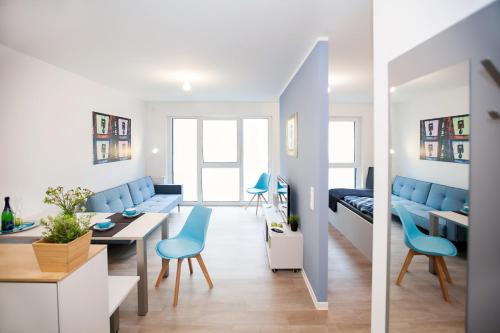 a living room with blue chairs and a dining room at Spreepolis Boardinghaus in Berlin
