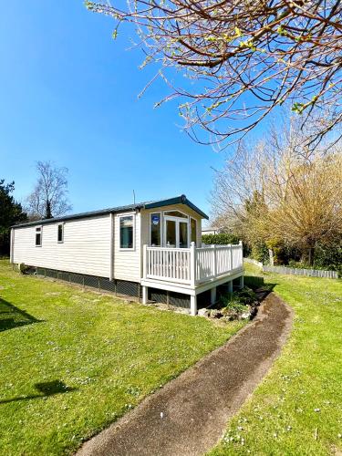 a small white house with a porch on a grass field at The Puffins Rest in Tenby