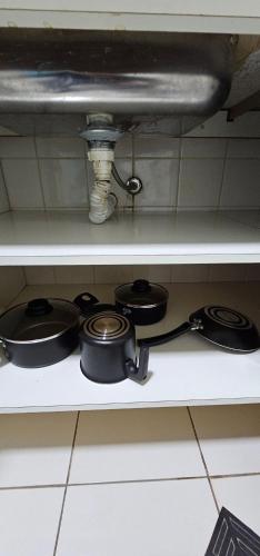 a shelf with pots and pans on a stove at Edifício Belluno in Ribeirão Preto