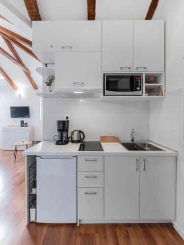 a white kitchen with white cabinets and a microwave at Apartment The Charm in Split