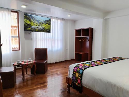 库斯科Kantu hotel的卧室配有一张床,墙上配有电视。