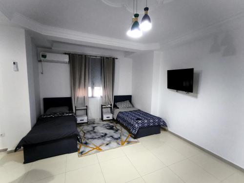 a bedroom with two beds and a flat screen tv at Appartement cosy à Reghaia Plage pour les familles in Reghaïa