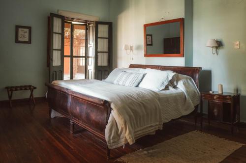 a bedroom with a wooden bed with white sheets and a mirror at Estancia La violeta in Chajarí