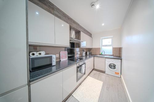 Una cocina con gabinetes blancos y un microondas. en Ilford Luxury Apartments, en Ilford