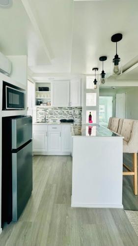 a kitchen with white cabinets and a black refrigerator at Modern 1BR Suite Boutique 5 Miles to Beach in Clearwater