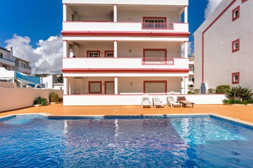 a villa with a swimming pool in front of a building at cozy sunny peaceful flat with swimming pool in Burgau