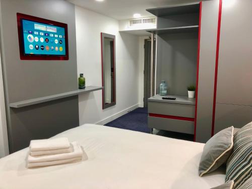 a bedroom with a bed with a tv on the wall at Ilford Hotel Goodmayes in Ilford