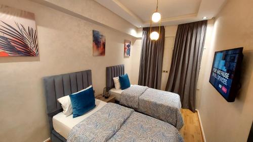 a hotel room with two beds and a flat screen tv at luxury apartment of 80m2 opposite HASSAN 2 MOSQU and SEA , near downtwn from family , INTERDIT COUPLES ARAABIC NON MARIÈ, FORBIDDEN UNMARRIED ARAABIC COUPLES , basement car park FREE in Casablanca
