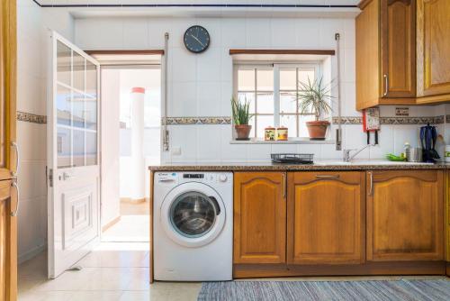 a kitchen with a washing machine in a kitchen at cozy sunny peaceful flat with swimming pool in Burgau