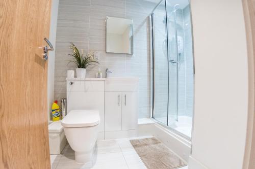 a white bathroom with a toilet and a shower at Ilford Tower Apartments in Ilford