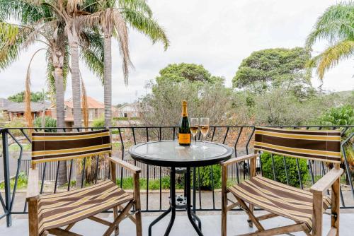 a table with two chairs and a bottle of wine on a balcony at Renovated Retro Apartment Near Harbour Front Walks in Sydney