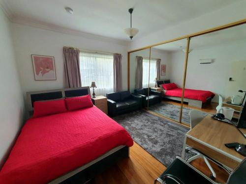 a bedroom with a red bed and a mirror at Holiday House in Sunbury Centre in Sunbury