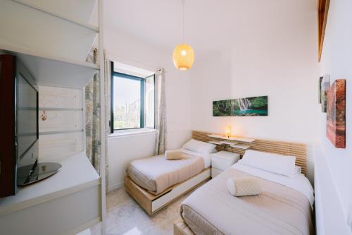 a white room with two beds and a tv at Infinity Experience Casa Vacanza Incantevole con Terrazzo in Scala