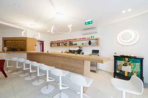 a restaurant with white chairs and a bar at Avis Hotel in Novalja