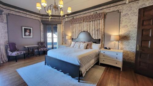 a bedroom with a bed and a dresser and a table at The New Victorian Mansion Bed & Breakfast in Saint Paul