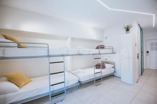 a room with white bunk beds in a room at Avis Hotel in Novalja