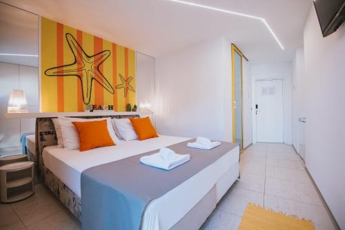 a bedroom with a large white bed with orange pillows at Avis Hotel in Novalja
