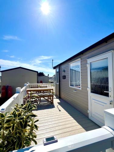 a deck with two wooden benches and a building at The Driftwood Den in Tywardreath