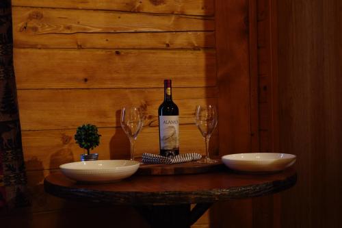 a bottle of wine sitting on a table with two glasses at Moose-AKa's Cabins in Healy