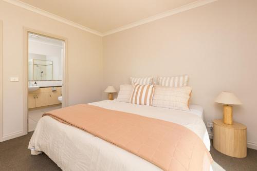 a white bedroom with a large bed and a mirror at Mildura City Centre Escape in Mildura