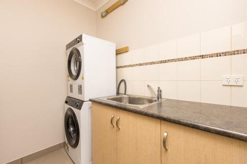 a kitchen with a sink and a washing machine at Mildura City Centre Escape in Mildura