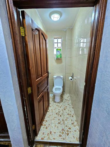 a bathroom with a toilet and a wooden door at pinlifehomes in Naro Moru