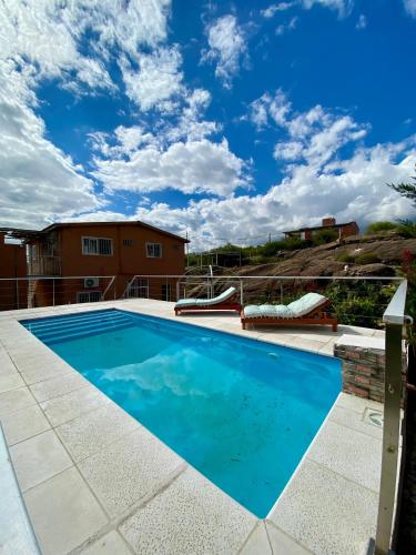 a swimming pool with a blue sky in the background at Clomplejo MUNAY con piscina y parking in Villa Cura Brochero