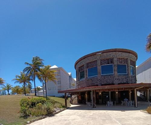 a brick building with tables and chairs on a beach at Une vague de plaisir in Saint-François