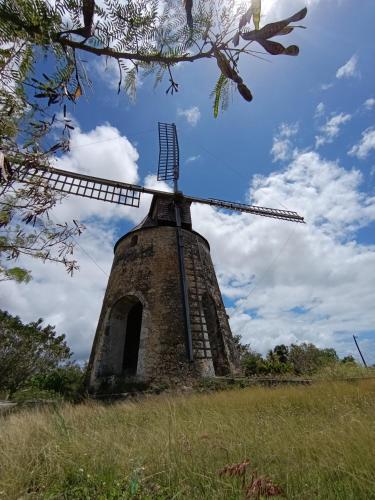 an old windmill in a field with a blue sky at Une vague de plaisir in Saint-François
