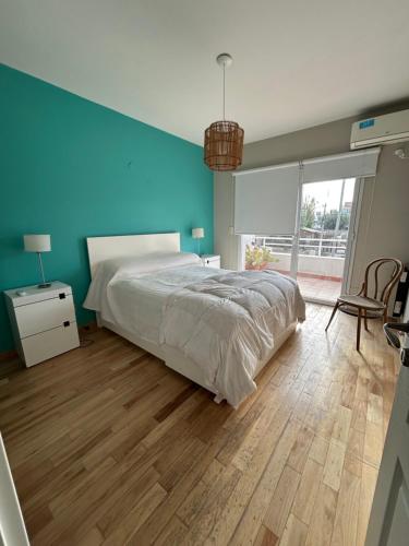 een slaapkamer met een groot bed en een blauwe muur bij Refugio Sur in Puerto Madryn