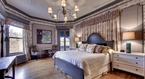 a bedroom with a bed and a dresser and a table at The New Victorian Mansion Bed & Breakfast in Saint Paul
