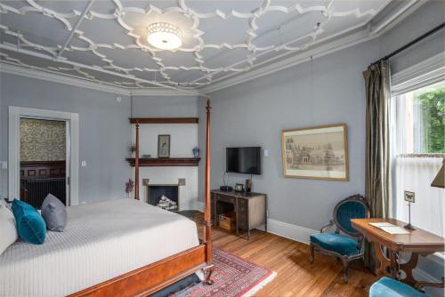 a bedroom with a bed and a desk and a fireplace at The New Victorian Mansion Bed & Breakfast in Saint Paul