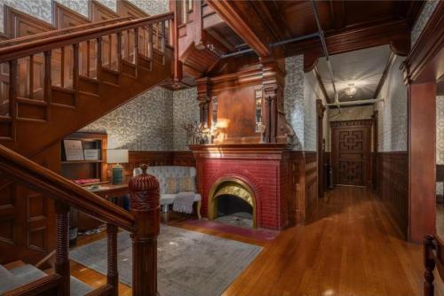 a living room with a fireplace and a staircase at The New Victorian Mansion Bed & Breakfast in Saint Paul