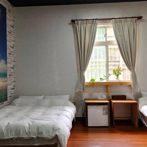 a bedroom with two twin beds and a window at 十畝田山莊會館 in Chishang