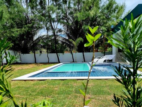 a swimming pool in a yard with two chairs around it at Casa Bela Vista in Japaratinga