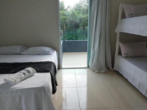 a room with two beds and a door to a balcony at Casa Bela Vista in Japaratinga