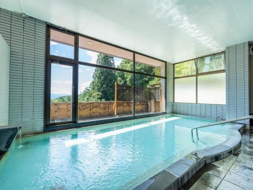 a large indoor swimming pool with a large window at Hishino Onsen Tokiwakan in Komoro