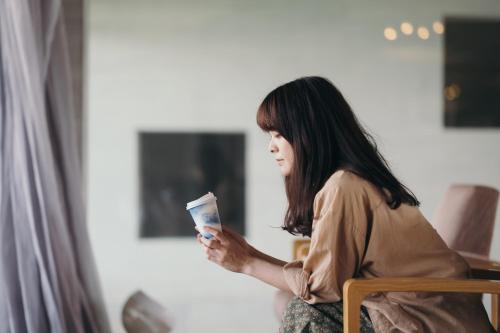 a woman sitting in a chair holding a cup at Setre Marina Biwako in Moriyama