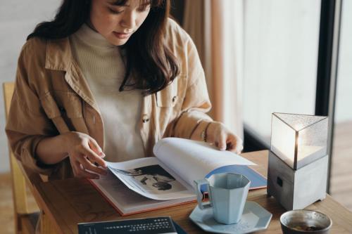 a woman sitting at a table reading a book at Setre Marina Biwako in Moriyama