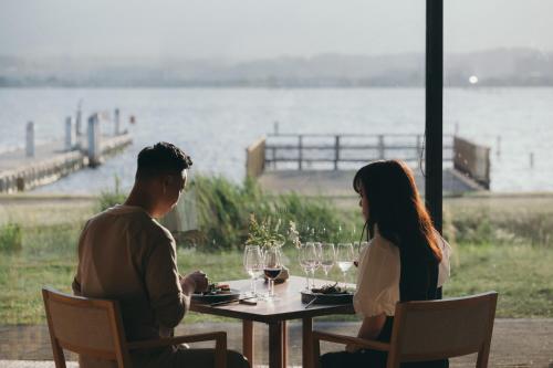 a man and woman sitting at a table with wine glasses at Setre Marina Biwako in Moriyama