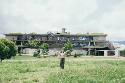 a man standing in a field in front of a building at Setre Marina Biwako in Moriyama