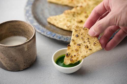 a person holding a cracker in a bowl of soup at Setre Marina Biwako in Moriyama