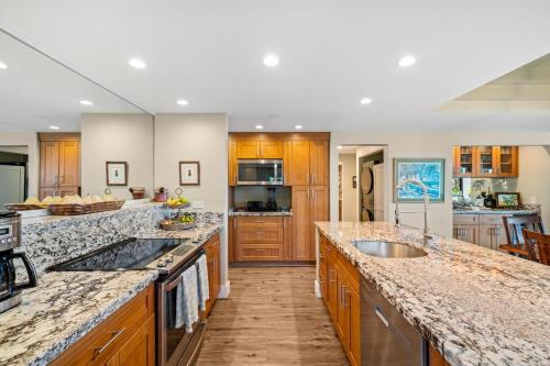 a large kitchen with wooden cabinets and granite counter tops at Kahana Village 36 · KHV 36 Oceanfront 3BD Kahana Condo, Beach & in Lahaina