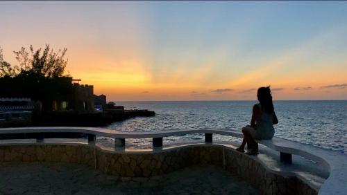 a woman sitting on a bench looking at the ocean at Begona Cliff Hotel in Negril