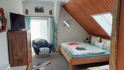 a bedroom with a bed and a tv and a chair at Villa Gast - Winzerwohnung, für Gruppen bis 9 Gäste in Kamp-Bornhofen