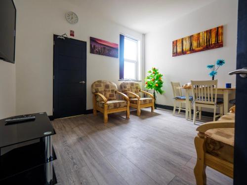 a living room with chairs and a table and a door at Chatham lodge Cosy Large Double Room 1 in Stoke on Trent