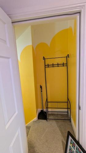 a room with a yellow wall with a metal rack at Stylish Condo on Victorian Seafront, Voyagers Rest Bexhill in Bexhill