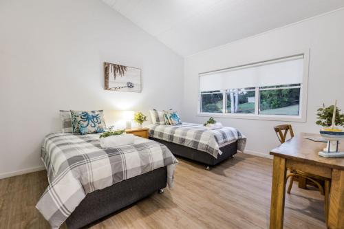 a bedroom with two beds and a table and a window at Slipaway 1770 in Seventeen Seventy